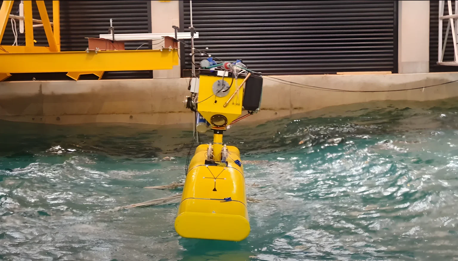 NoviOcean scale prototype under instrumented testing in a wave tank, hydraulic power take-off visible